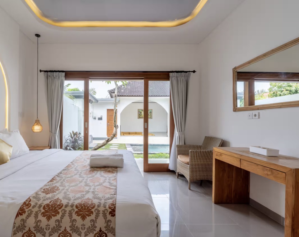 Villa Garden Court in Canggu, Bali: bright bedroom with a wooden desk and rattan chair opening onto a sunny garden courtyard.